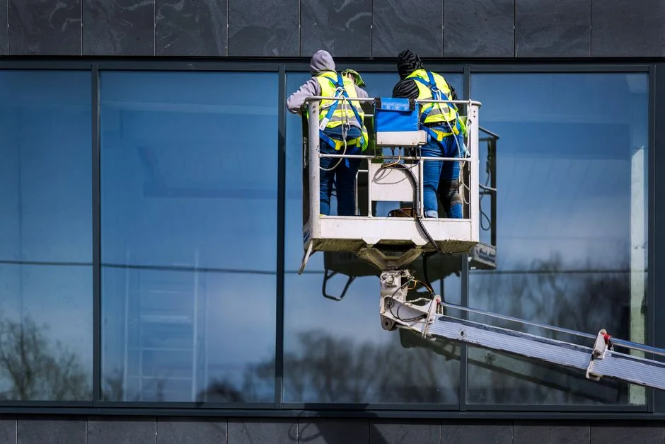 services-03 A man cleaning skyscraper windows with a harness, showcasing urban high-rise work.